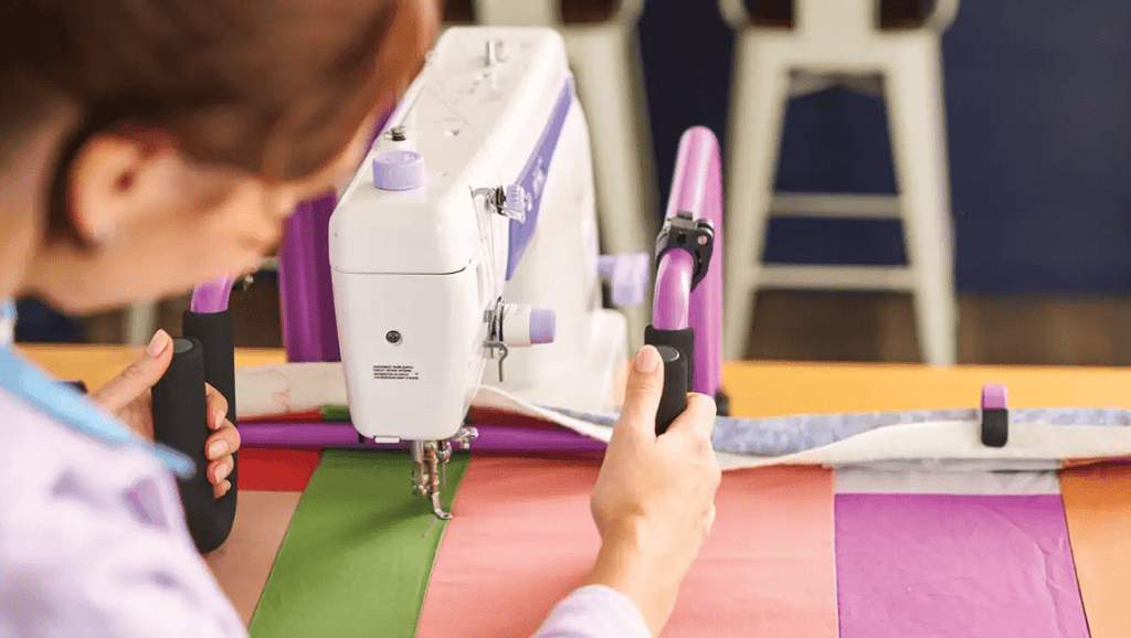 Handi Quilter FreeWay Quilt Frame; white quilting machine on a purple frame quilting colorful fabric