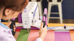 Handi Quilter FreeWay Quilt Frame; white quilting machine on a purple frame quilting colorful fabric