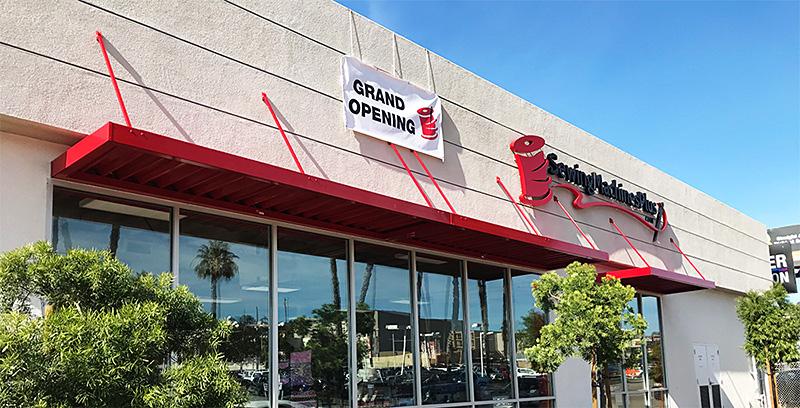 Storefront with a 'Grand Opening' sign and a logo of Sewing Machine Plus.