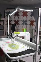 Handi Quilter HighLight 2 5' white LED lighting system mounted on a quilting frame; green thread spool and MOXIE