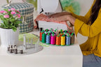 Bluefig Designer Series Pearl Mini Carry Case on a sewing table beside a sewing machine with colorful thread spools.