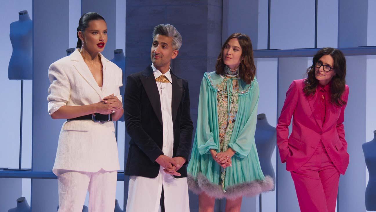 4 person standing in a row and a women is hosting a program