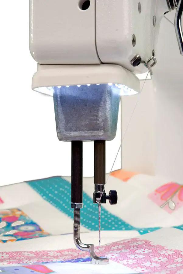 Handi Quilter Sweet Sixteen long-arm quilting machine; white body with bright LED needle light over colorful quilt fabric.