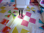 Handi Quilter Sweet Sixteen long-arm sit-down quilting machine quilting a colorful patchwork quilt