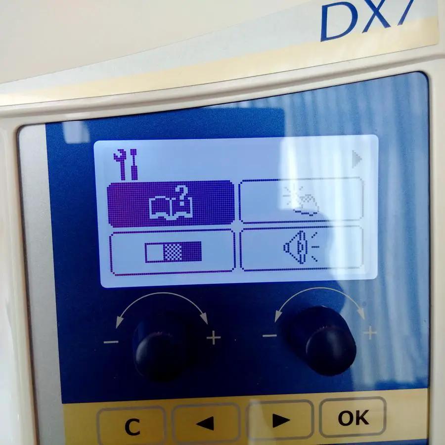 Juki HZL-DX7 sewing machine control panel with blue LCD display and two adjustment dials