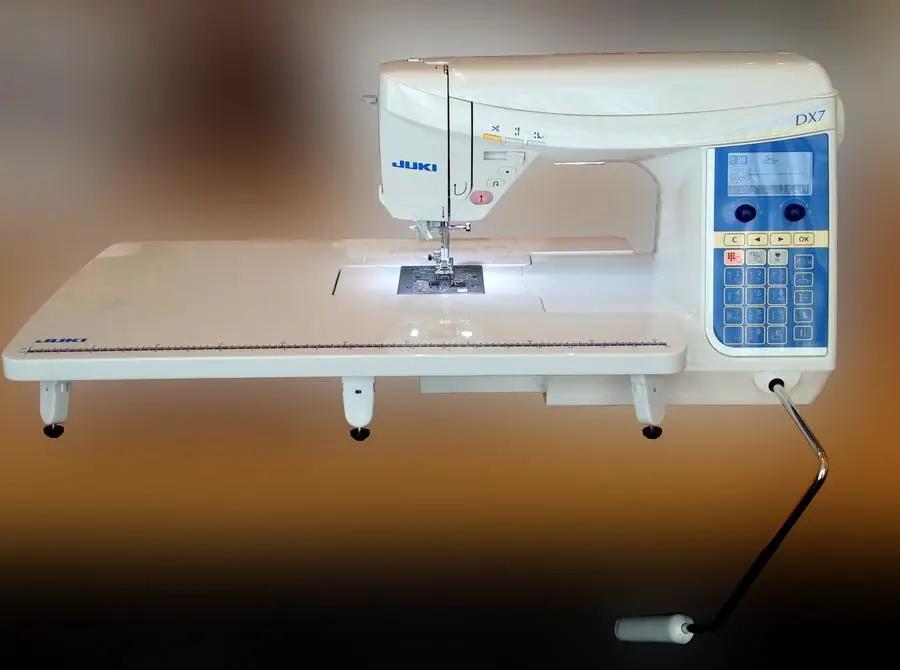 Juki HZL-DX7 sewing machine with blue keypad control panel on a white table.