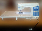 Juki HZL-DX7 sewing machine with blue keypad control panel on a white table.