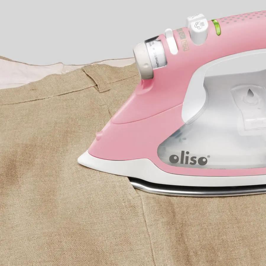 Limited Edition Oliso Pro TG1600 pink smart iron on beige fabric, Oliso branding visible.