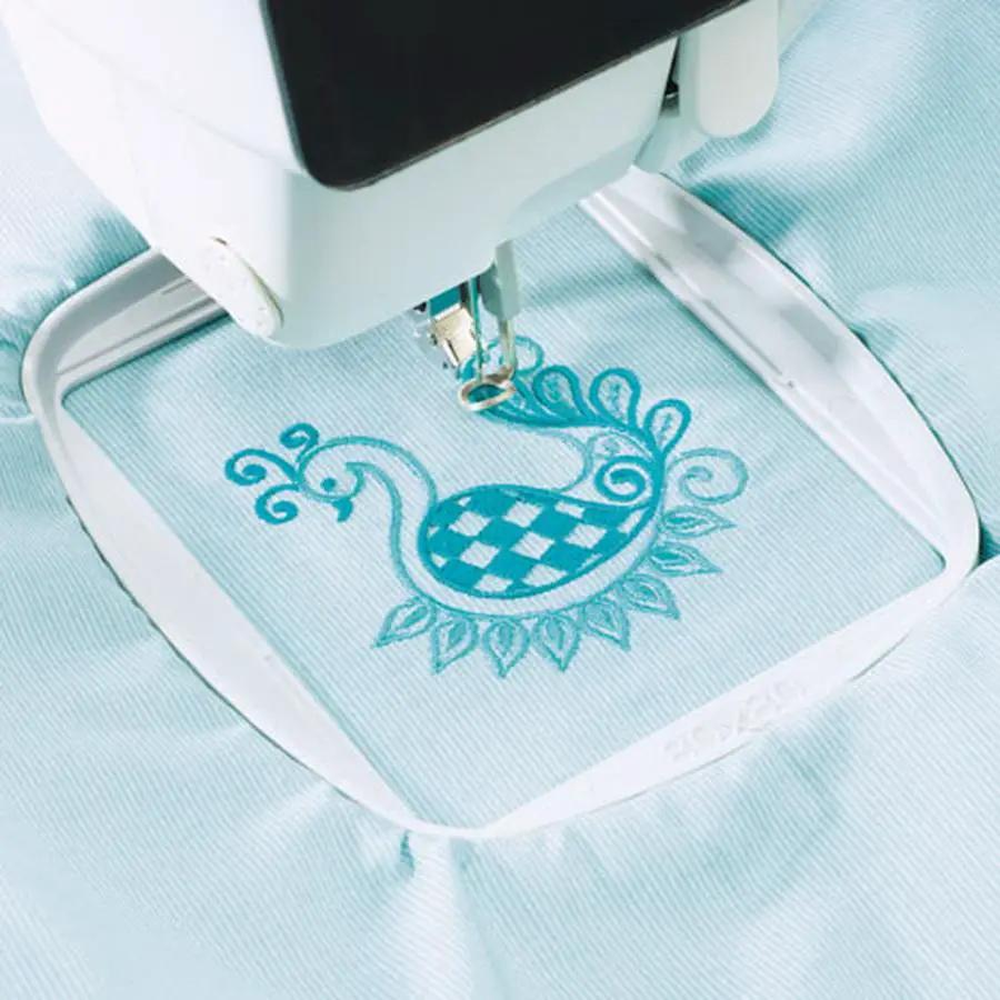 Sew Tech 80mm x 80mm embroidery hoop on light blue fabric with teal embroidery.