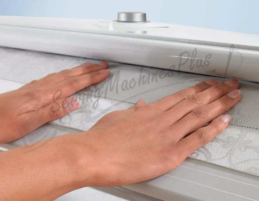 Miele HM 16-80 Rotary Iron with Steam, white metal finish, hands pressing fabric on the roller.