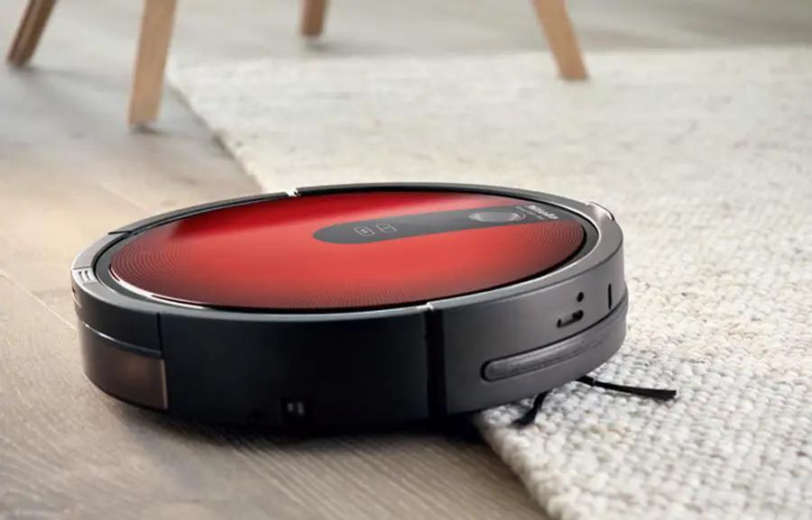 Miele Scout RX1 red robotic vacuum on carpet, black body.