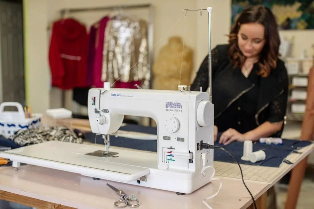 Baby Lock Accomplish 2 sewing machine on a table; white mechanical machine with visible brand logo.