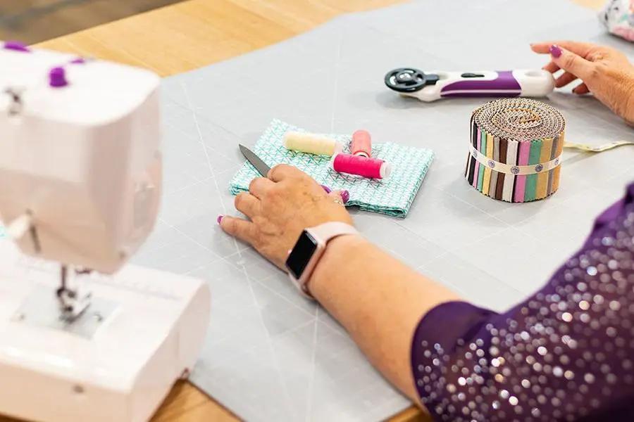 Crafters Companion Threaders A1 Cutting Mat on a craft table with rotary cutter and thread spools