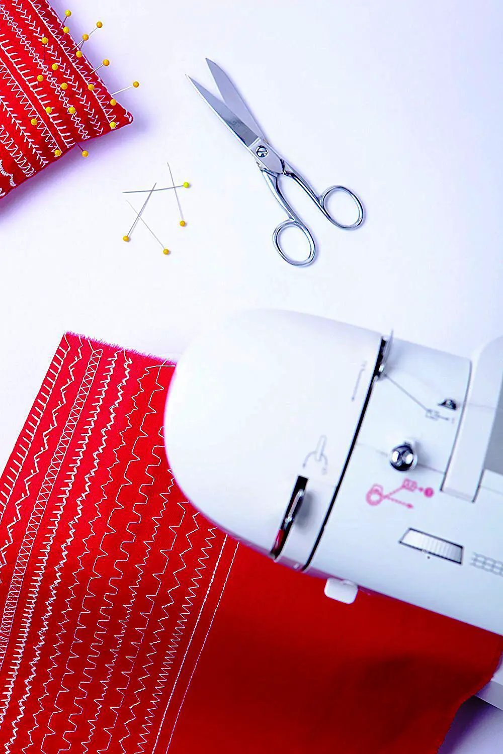Singer Fashion Mate Sewing Machine white; red fabric with zigzag stitching, scissors and pins nearby
