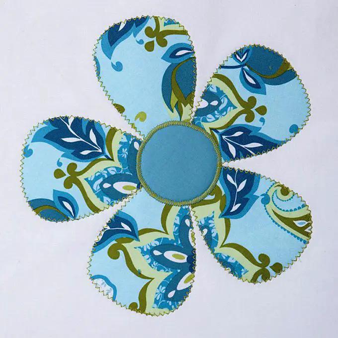 Flower-shaped pincushion in blue patterned fabric with a solid blue center.