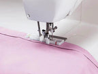 Singer Starlet sewing machine on pink fabric with white body and presser foot