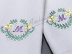 Singer S10 Studio embroidery on white fabric showing two green leaf wreaths with purple M monograms