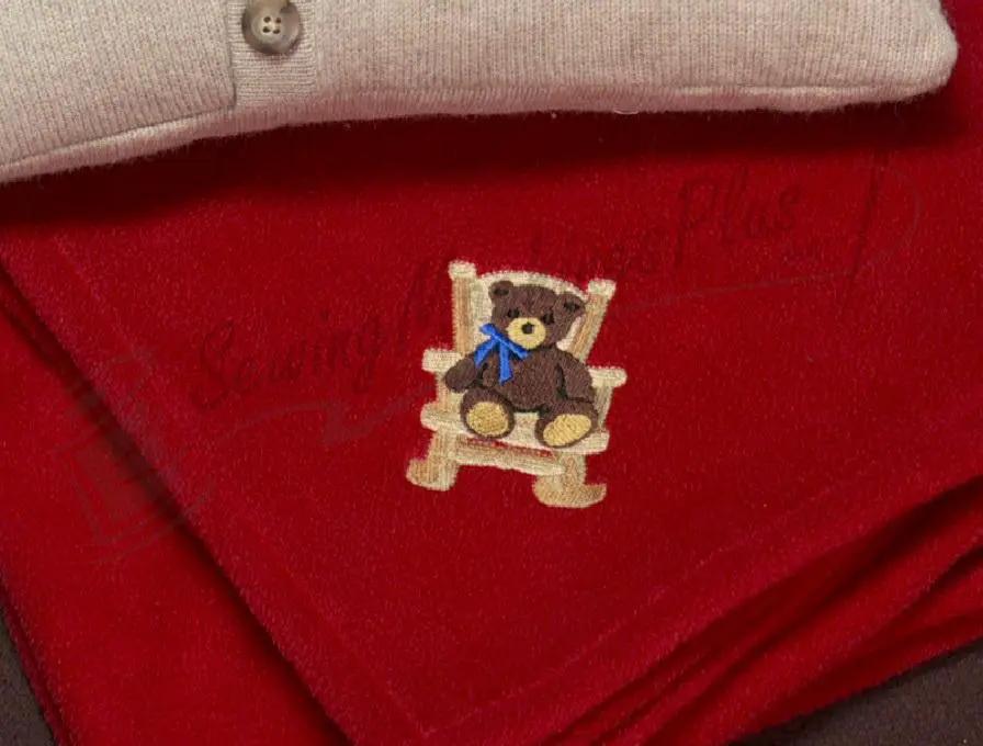 Embroidery fabric: red fleece featuring a teddy bear on a wooden chair