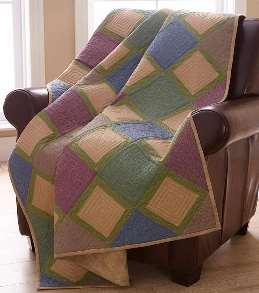 Dime Our House Cheater Quilt, pastel square blocks in peach, blue, purple and green draped over a leather chair