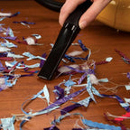 Carpet Pro Teeny Tiny Tank handheld vacuum SCT-1.2, black, cleaning colorful confetti on a wooden floor