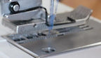 Janome Refurbished 1000CPX Cover Pro coverstitch machine, silver-gray, close-up of needle and presser foot.
